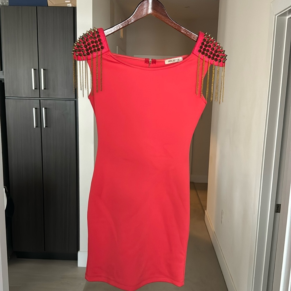 Coral colored mini dress with spiked and tasseled shoulders. Zip up back